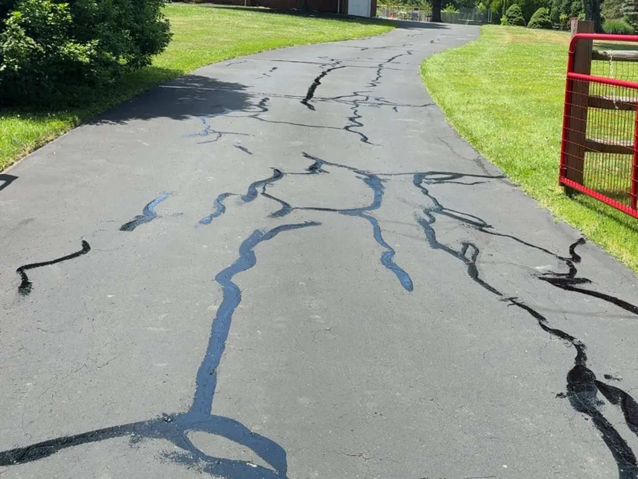 Driveway with visible crack-fill sealant lines running along an asphalt surface