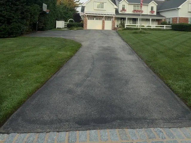 Residential driveway with faded, graying asphalt before sealcoating