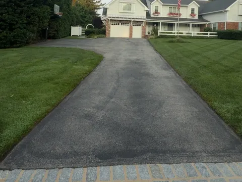 Residential driveway with faded, graying asphalt before sealcoating