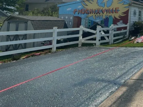 Same driveway freshly sealcoated, garage with Phoenixville mural in background