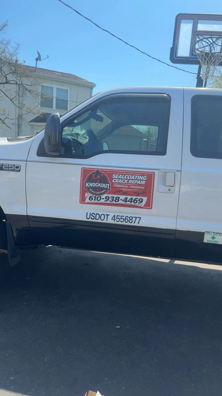 Knockout Sealcoating's branded Ford F-250 — phone 610-938-4469 and USDOT 4556877 visible on the door